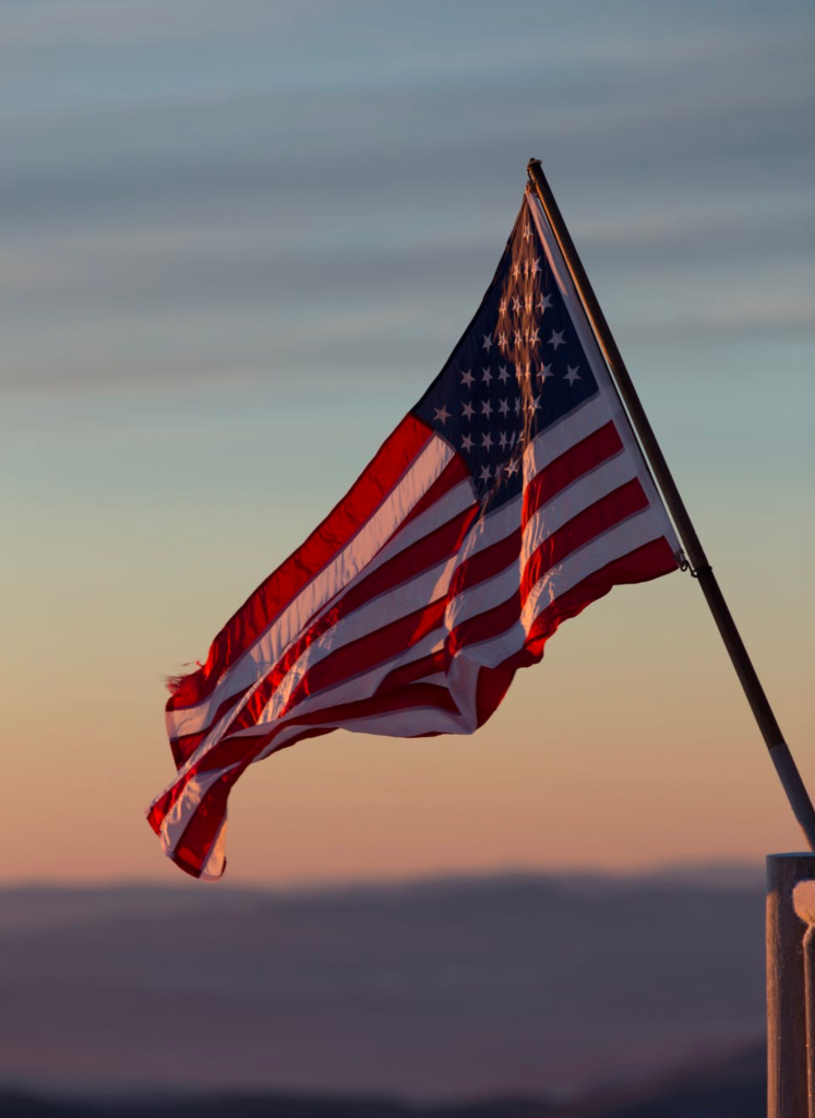 small American flag blowing in the wind at sunset